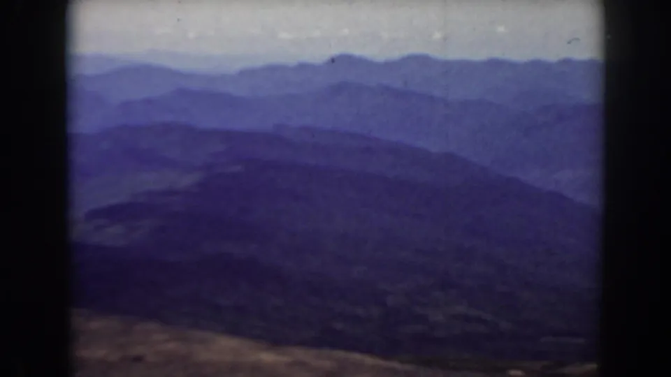 Archival 8mm frame from Mount Washington showing layered Appalachian ridges with grain, haze, and dark borders.