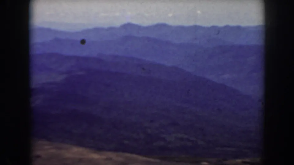 Late frame of the 1938 Mount Washington panorama with hazy ridges, foreground slope, and visible dust mark on the film.