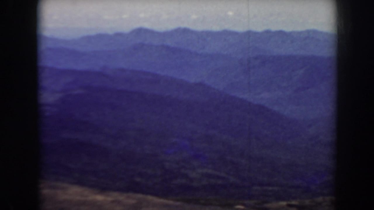 Distant blue-toned mountain ridges under a pale sky within an 8mm frame border.
