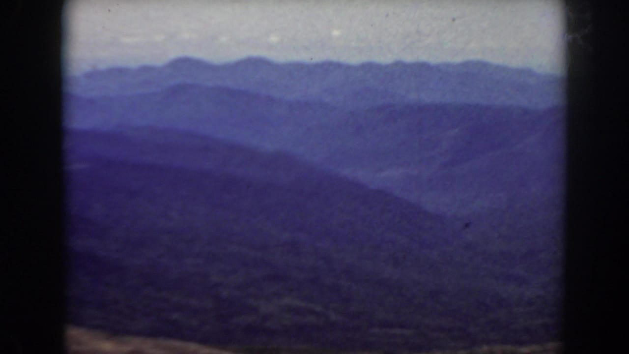 Mount Washington-area mountain view on 8mm film, with overlapping ridgelines, haze, and visible frame borders.