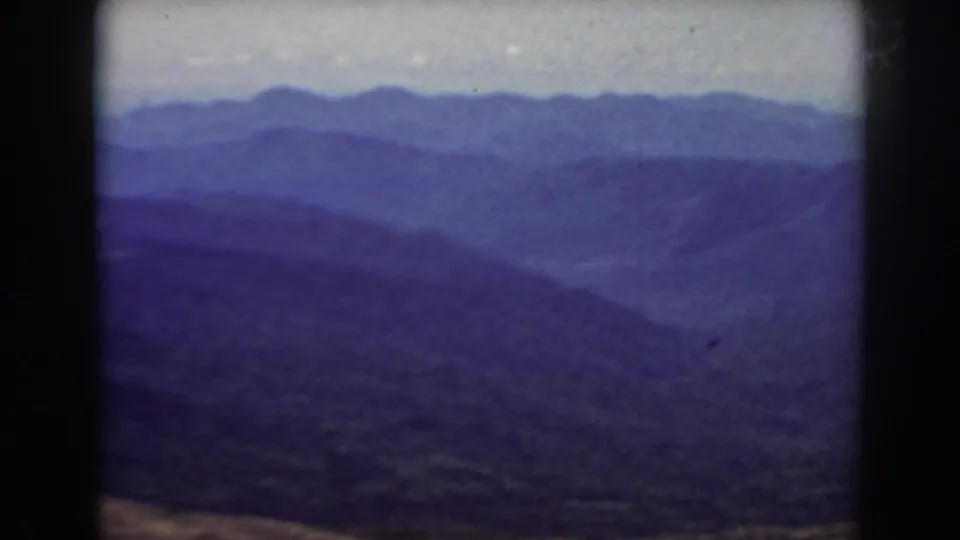 Mount Washington-area mountain view on 8mm film, with overlapping ridgelines, haze, and visible frame borders.