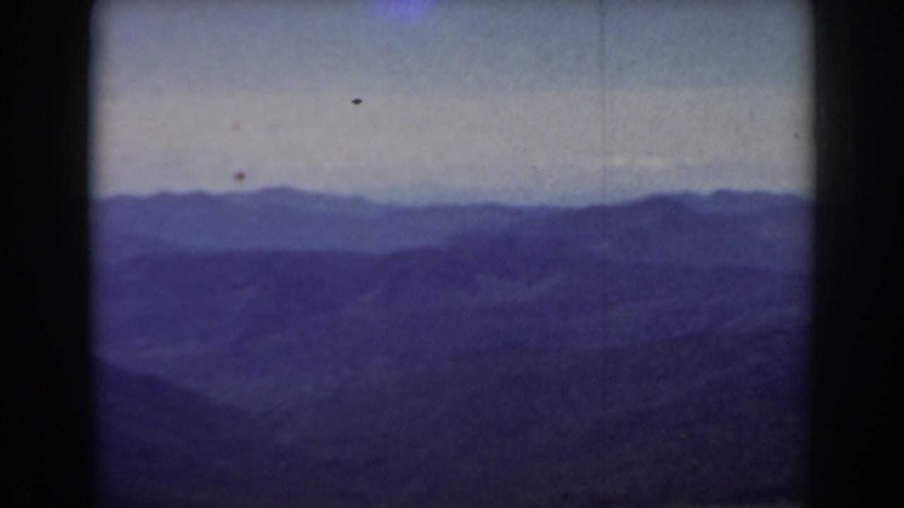 Distant blue mountain ranges beneath a pale sky with dark foreground ridges.