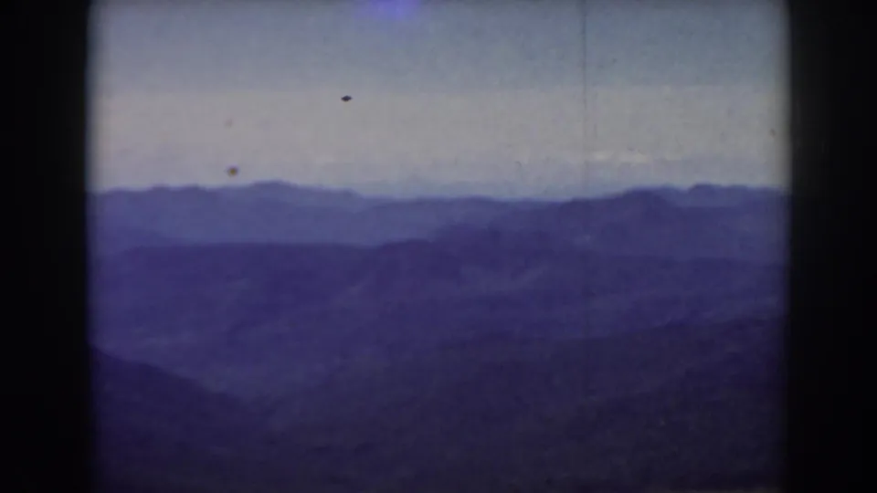 1938 Mount Washington area view with layered blue mountain ranges, pale sky, and dark rolling terrain in the foreground.