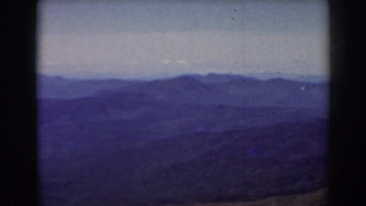 Soft panoramic view of mountain ridges with a pale horizon and dark foreground.
