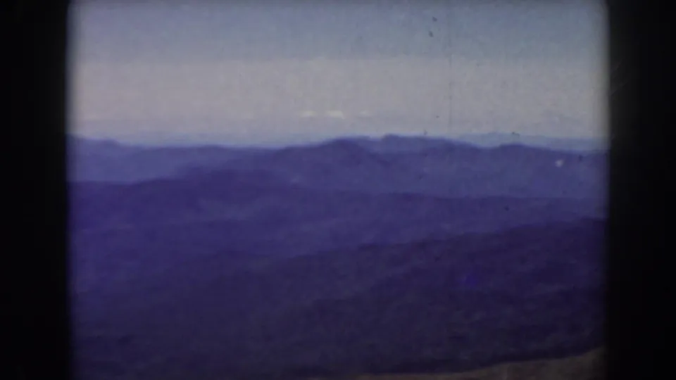 1938 Mount Washington area panorama showing distant ridge lines, muted sky, and a dark hillside edge in soft 8mm color.