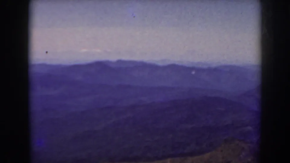 1938 Mount Washington area landscape with blue-toned mountain layers, a low pale sky, and rolling dark terrain in front.