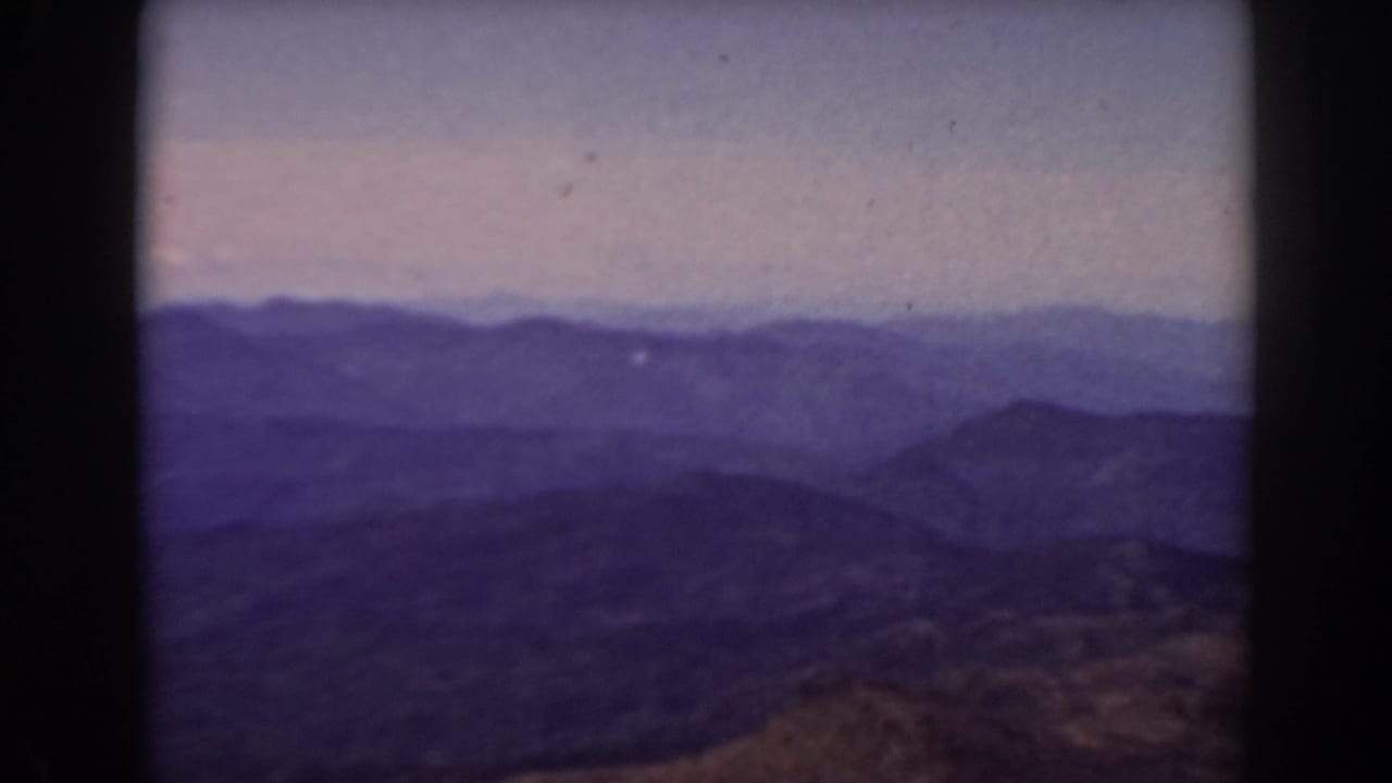 Layered mountain ridges under a hazy sky with dark 8mm frame edges.