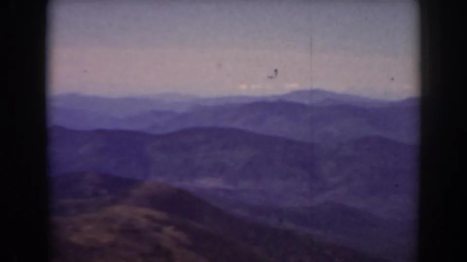 Late-1930s 8mm landscape frame showing Mount Washington area ridges with visible dust specks, soft exposure, and faded color.