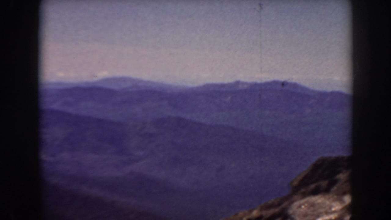 Distant blue-purple mountain range seen through dark film borders.