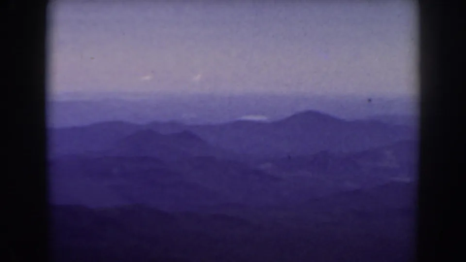 Mount Washington home-movie frame from 1938 showing a quiet blue-purple mountain range and hazy sky with visible 8mm frame edges.