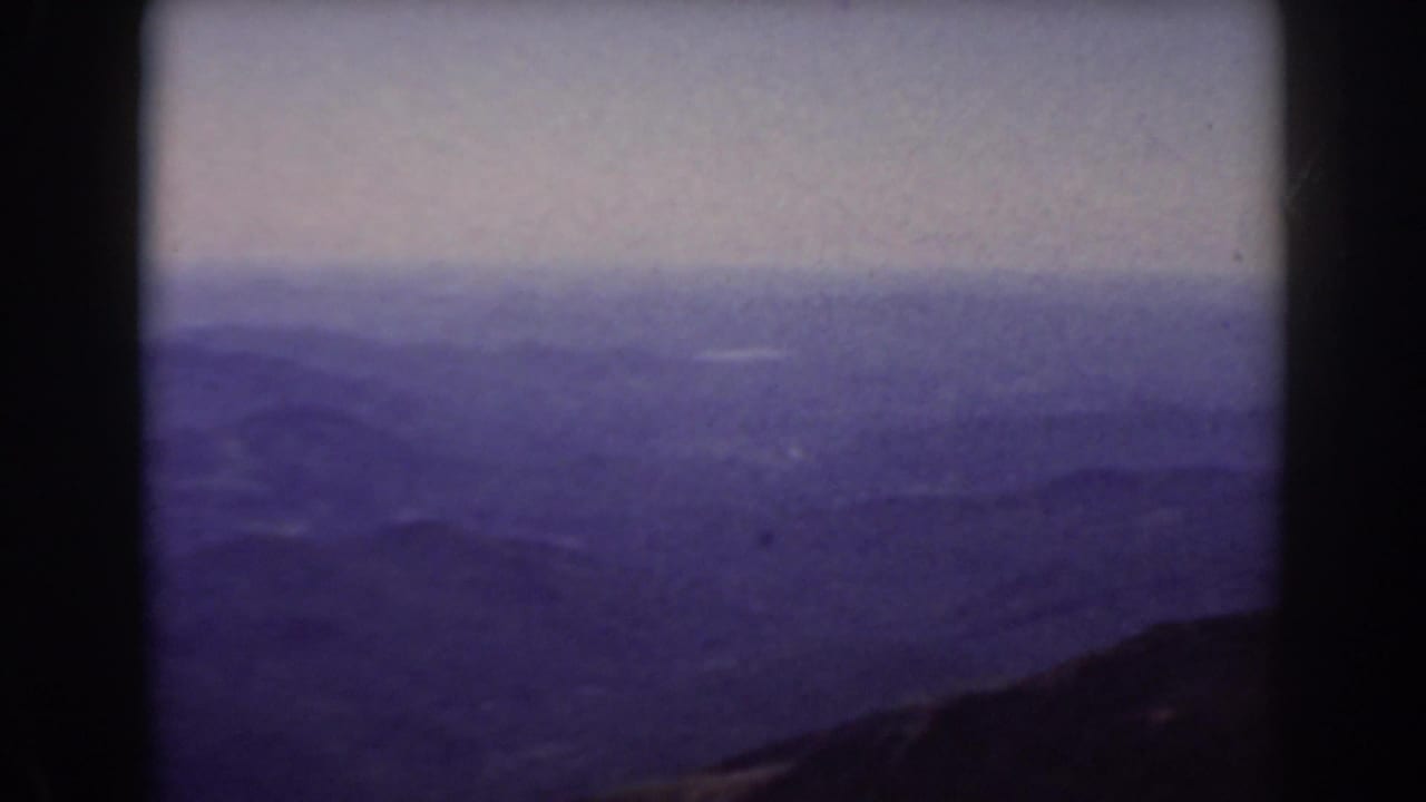 Hazy mountain ranges under a pale sky with a dark ridge in the foreground.