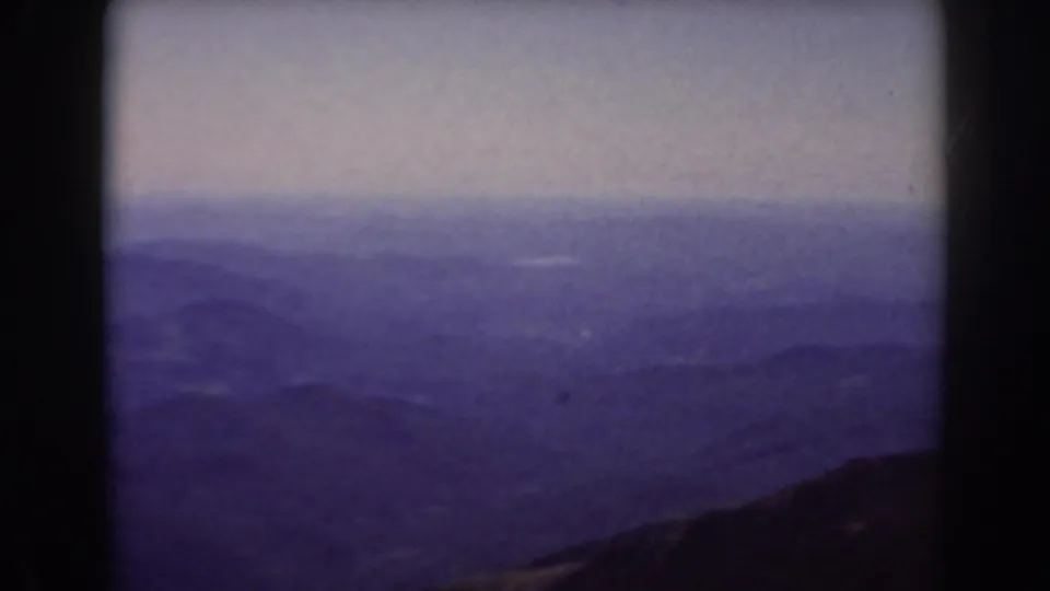 1938 8mm view from Mount Washington showing layered New Hampshire mountains fading into haze beneath a pale sky.