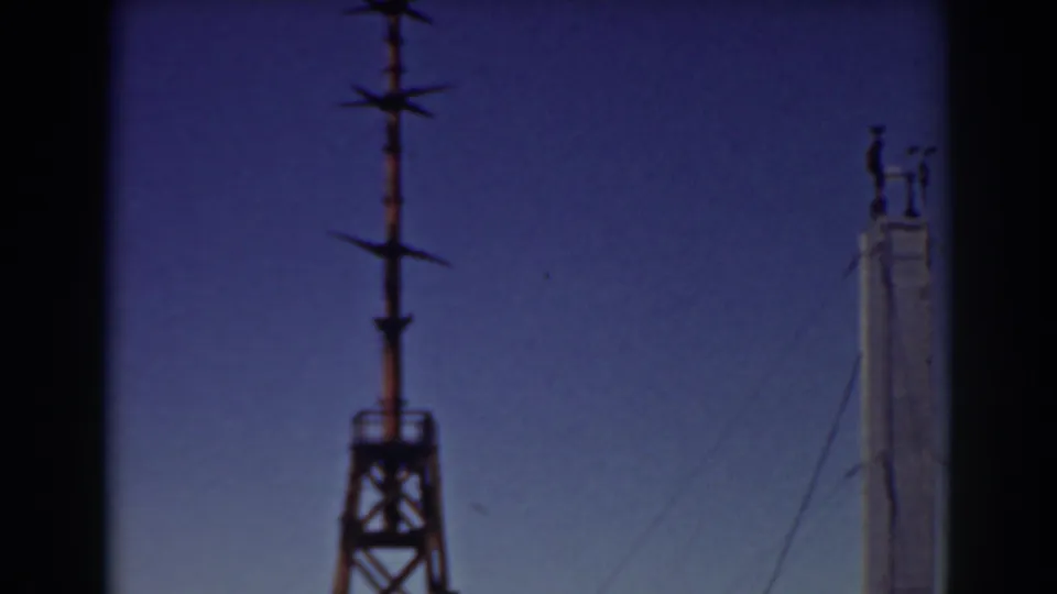 Workers appear near the top of a tall pole on Mount Washington, with wires and a lattice tower nearby in 1938 footage.