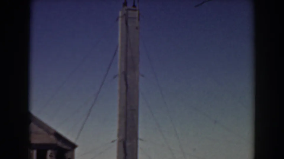 1938 Mount Washington home-movie frame showing a tall wooden tower and support wires against blue sky.