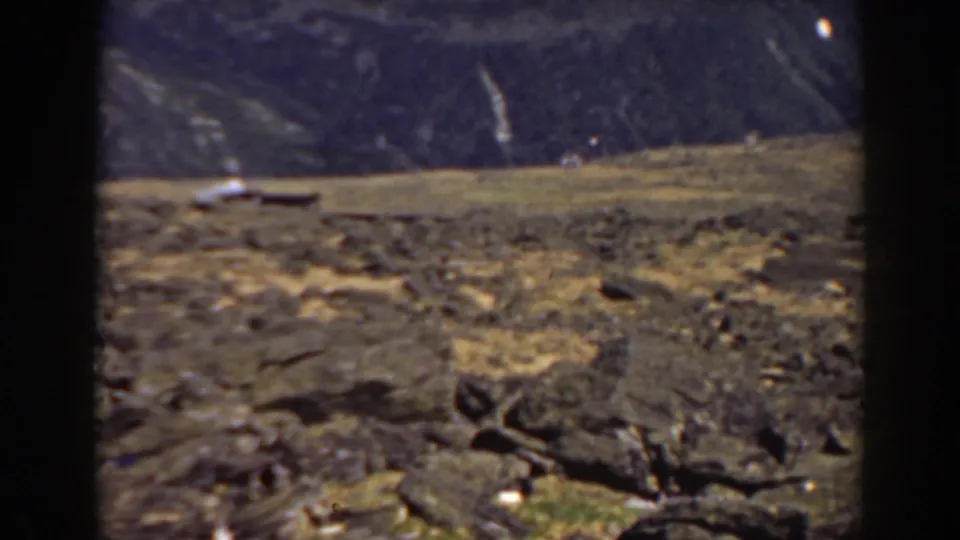 Mount Washington, New Hampshire landscape with rocky terrain, dry grass, and a small light object near the horizon.