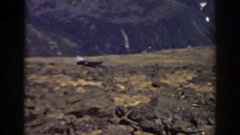1938 8mm frame of Mount Washington terrain with a distant slope and a small pale object on the horizon.