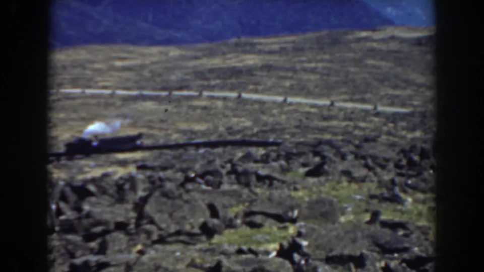1938 Mount Washington frame showing the steam locomotive backing along the mountain track near a hillside railing.