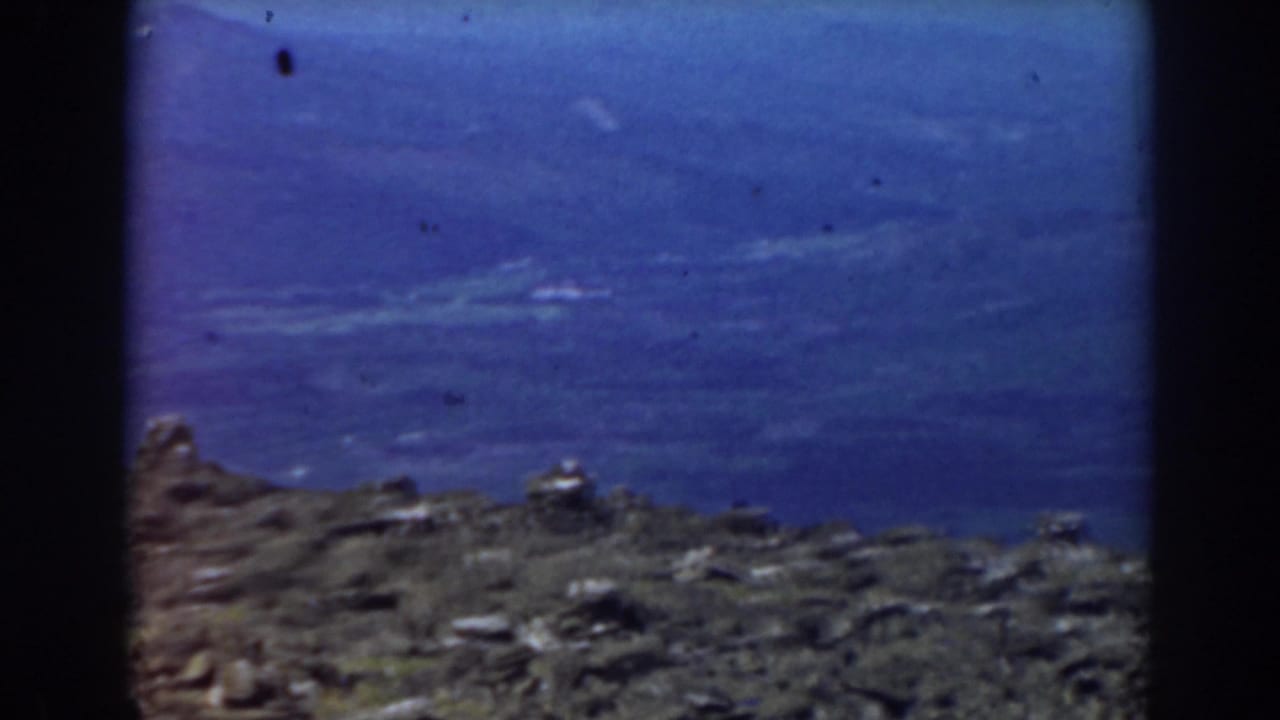Rocky mountain foreground beneath a dark blue sky with faint cloud bands.