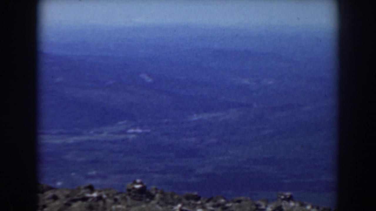 Hazy blue mountain ridges beyond a dark rocky ledge.