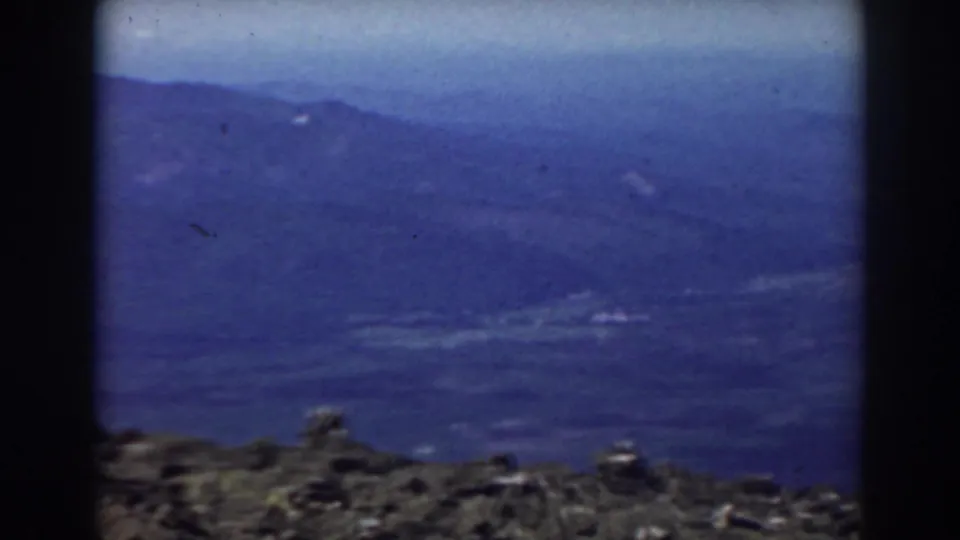 1938 Mount Washington landscape looking over a rough rock foreground toward layered mist-covered White Mountain ridges.