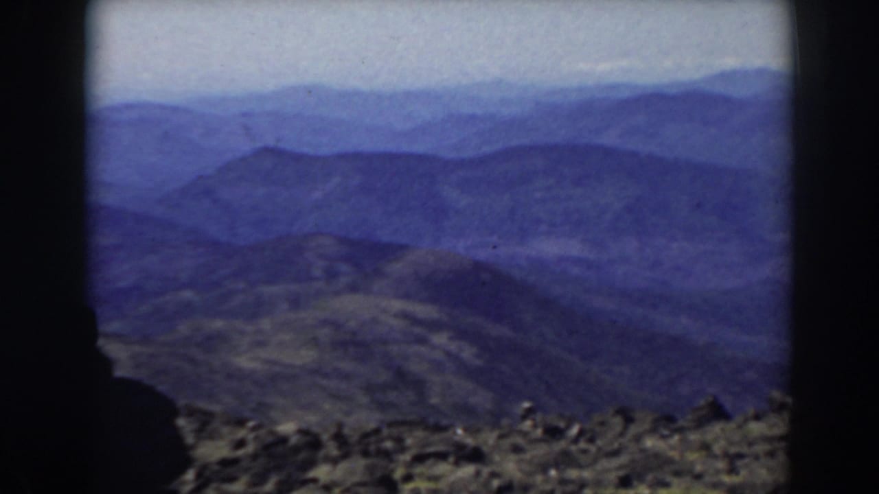Mountain ridges recede into a hazy blue distance above rocky ground.