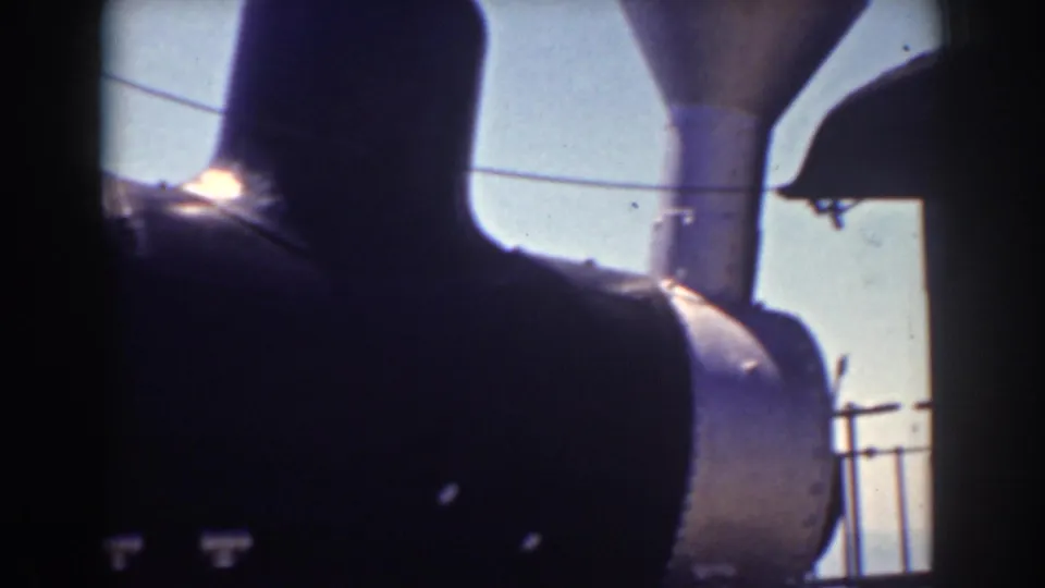 1938 Mount Washington footage showing a close, shadowed view of a steam locomotive stack, boiler front, railing, and sky.