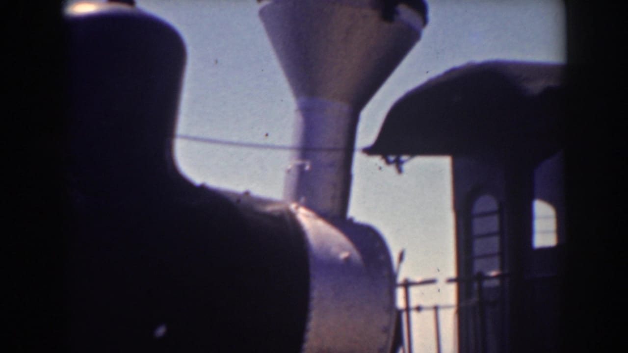 Dark steam locomotive silhouette with smokestack against a bright sky.