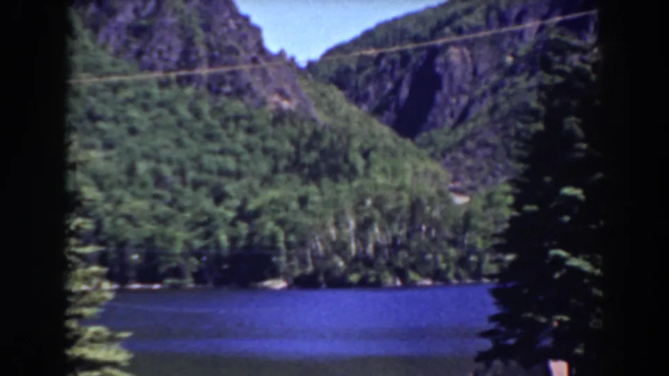 1938 Mount Washington-area landscape frame with blue lake water, green wooded hills, rocky mountain walls, and visible 8mm gate borders.