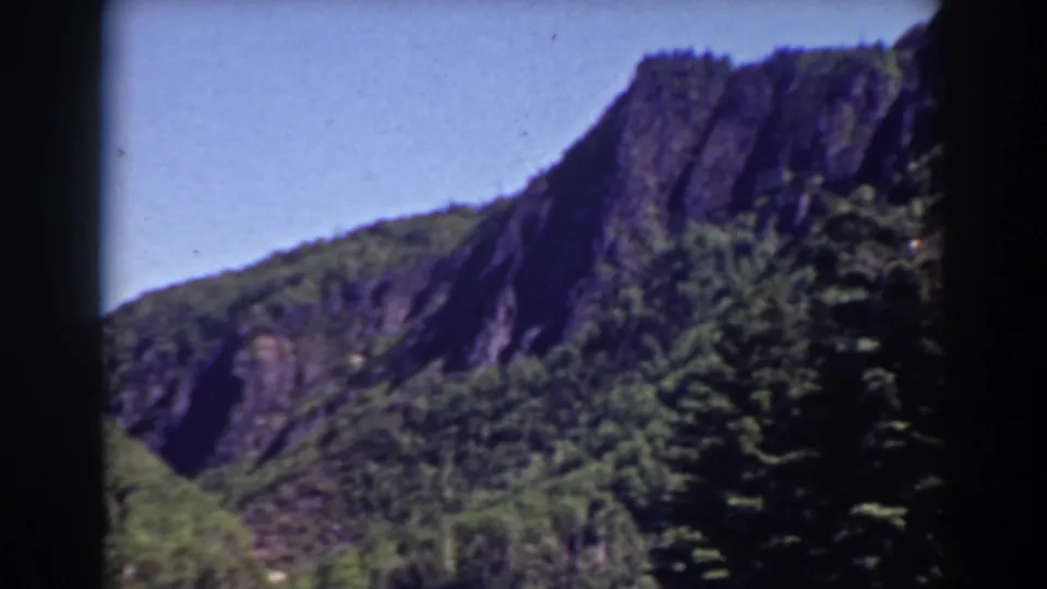 1938 8mm view of Mount Washington, New Hampshire, showing a rocky peak above dense green trees and dark film-frame edges.