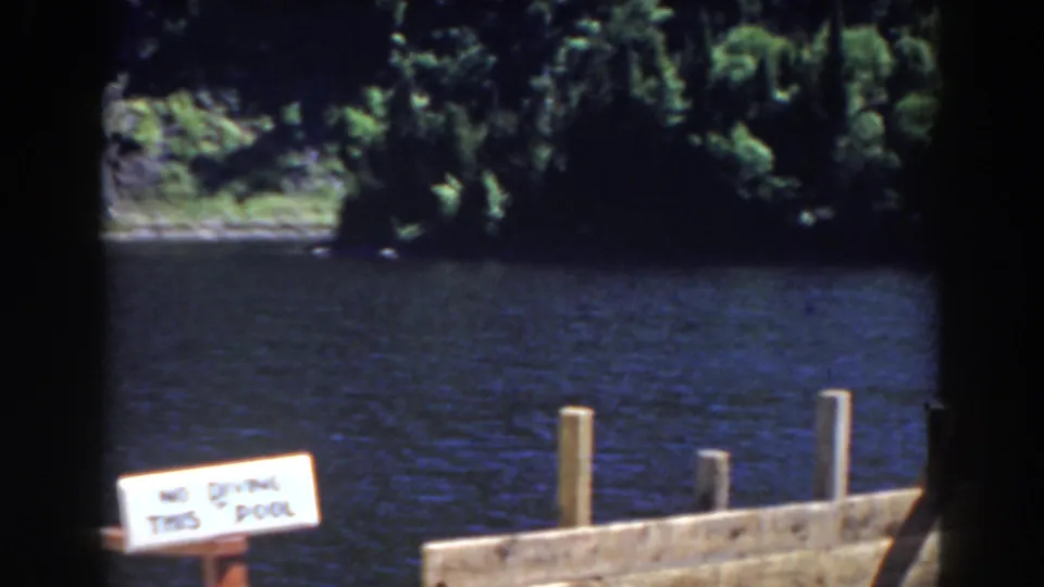 1938 Mount Washington, New Hampshire 8mm frame showing the no-diving sign near dock posts, dark water, and dense trees across the shore.