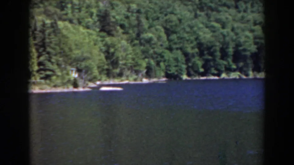 1938 Mount Washington area home-movie view of a blue lake and dense forest shoreline, with dark film-frame borders visible.