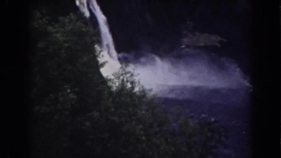 1938 Mount Washington home-movie frame showing water falling past trees into a shadowed, mist-filled lagoon.