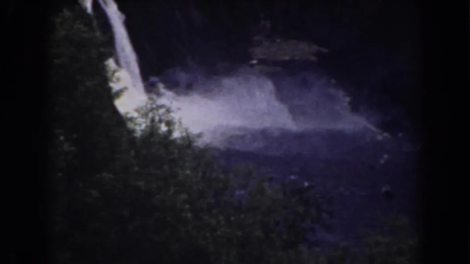 A bright stream falls near dense foliage, sending pale spray across a dark lagoon in the Mount Washington scene.
