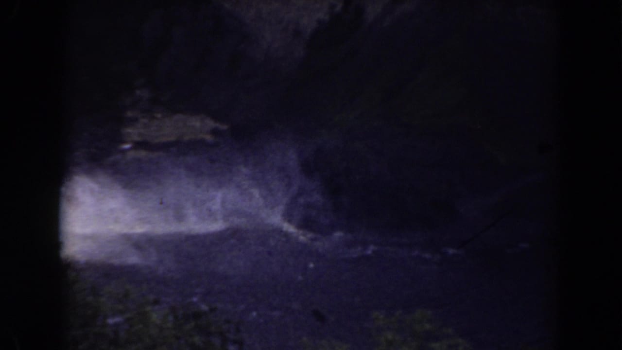 Dark river water moving past pale rock and shadowed terrain.