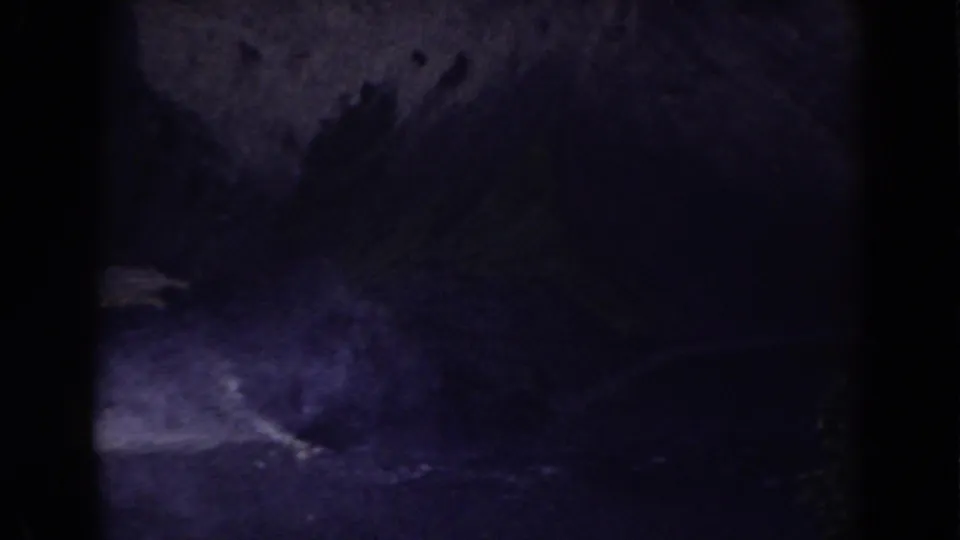 A dark 8mm frame from Mount Washington shows pale moving water crossing a rocky, heavily shadowed landscape.