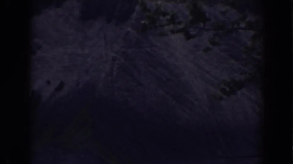 A shadowed Mount Washington river view shows faint water movement, rough rocks, and possible moss or vegetation in low light.
