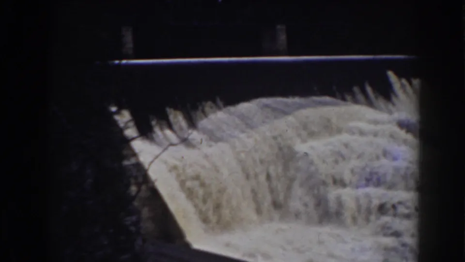 A man-made waterfall or dam spillway in Mount Washington, New Hampshire, with white water pouring through a dark wooded frame.