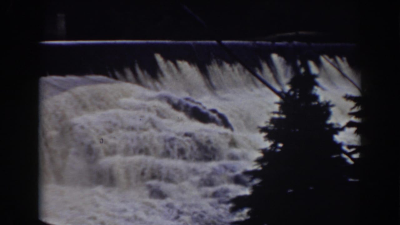 1938 8mm Mount Washington footage showing white water over a ledge, dark rocks, and a silhouetted pine in the foreground.