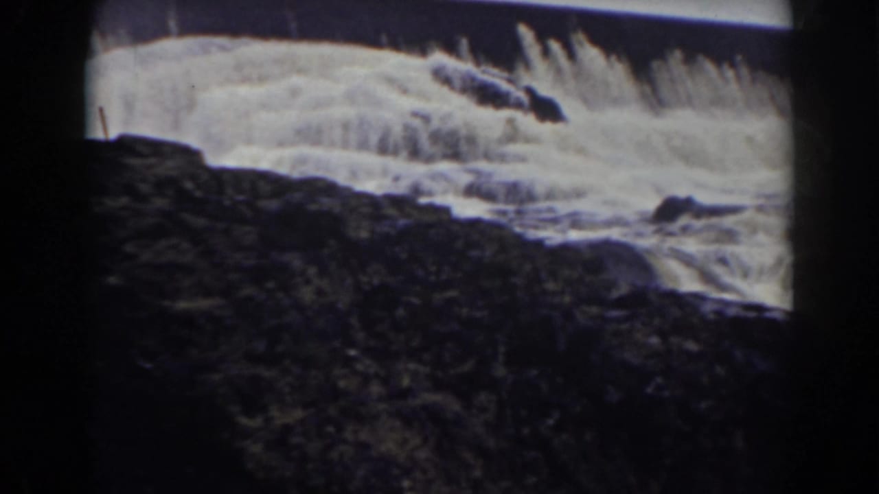 Bright water cascades over a ledge above a dark rocky foreground.