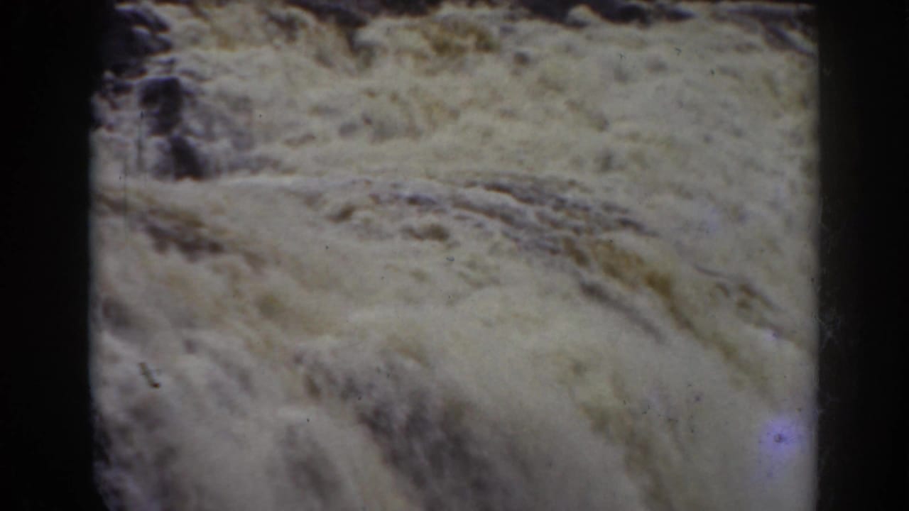 Close 1938 8mm frame of turbulent falls water at Mount Washington, with rocks partly visible through foam.