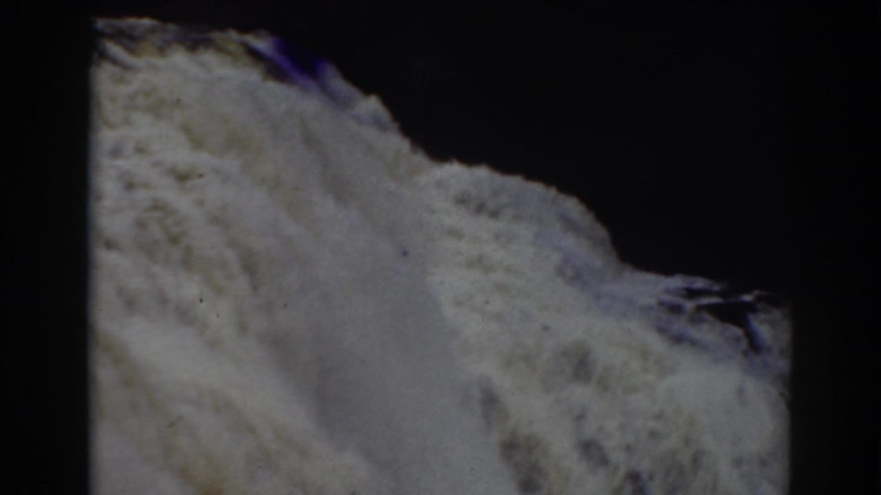 Close-up of waterfall foam spilling over an uneven rock shelf.