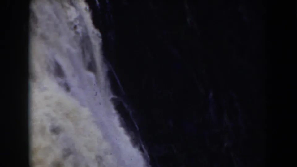 Mount Washington area waterfall detail showing white water beside a dark vertical rock channel, recorded with grainy 8mm home-movie texture.