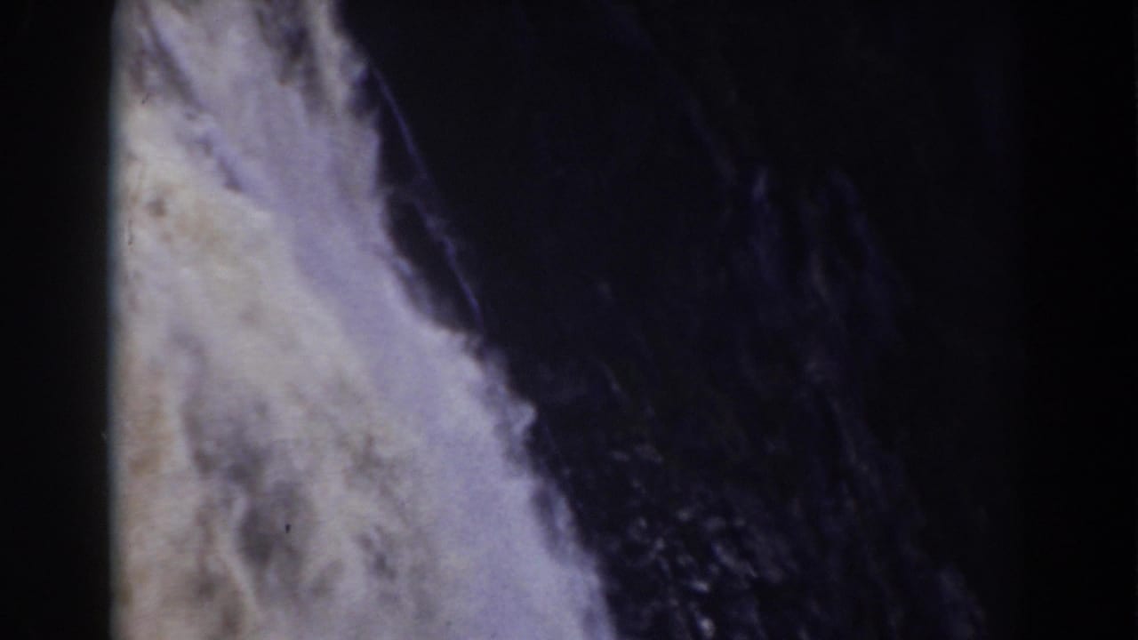 Close view of Crystal Cascade water against a shadowed rock face, with visible 8mm grain, soft focus, and faded color from the 1938 footage.