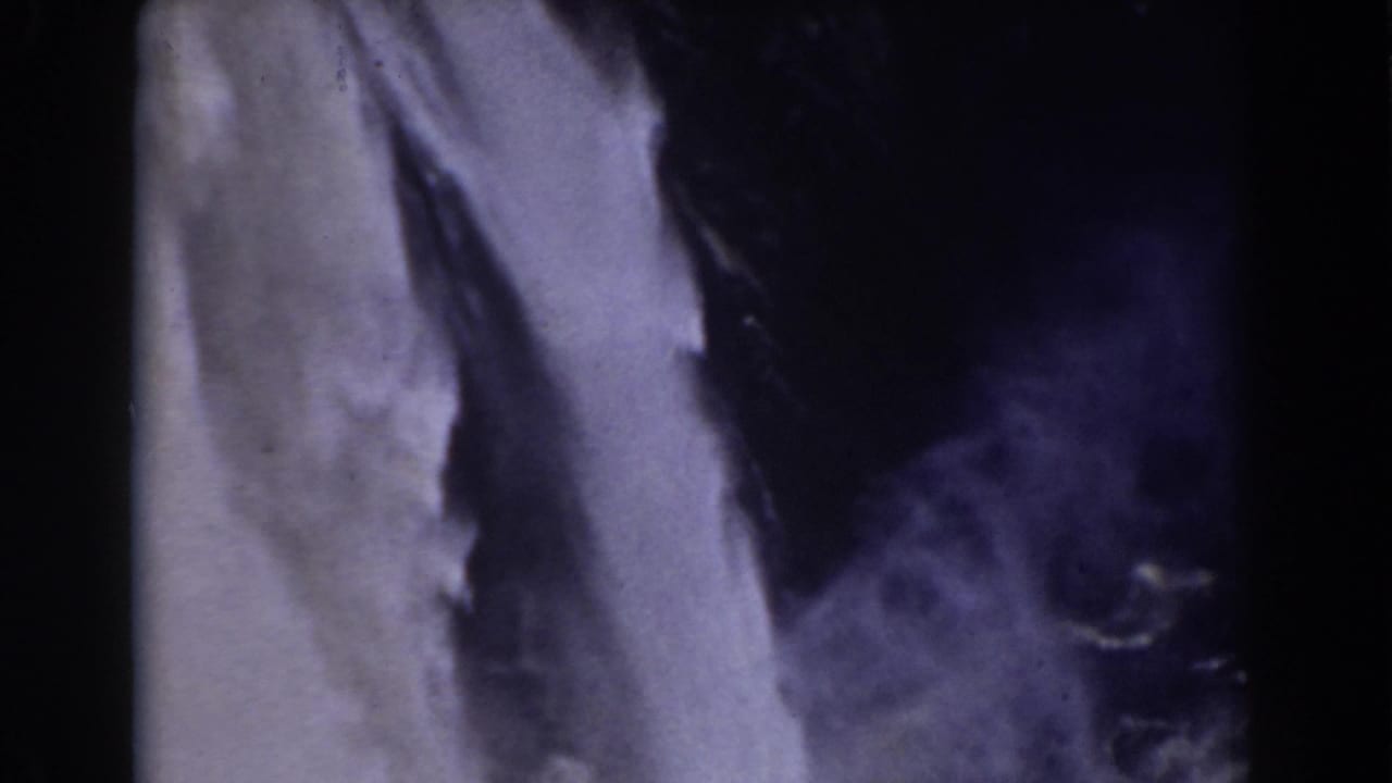 Tall waterfall fills the frame, with dark rock and spray visible at the side.