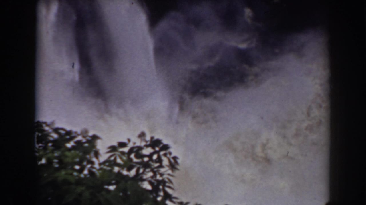 1938 Mount Washington home-movie frame showing waterfall spray behind silhouetted tree branches and dark film borders.