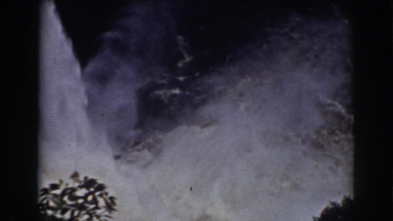 Close view of waterfall spray and mist with tree silhouettes at the lower edge.