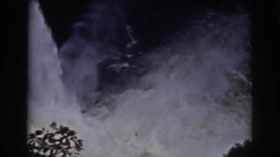 Mist from a Mount Washington waterfall dominates the frame, with dark branches and 8mm film edges visible.