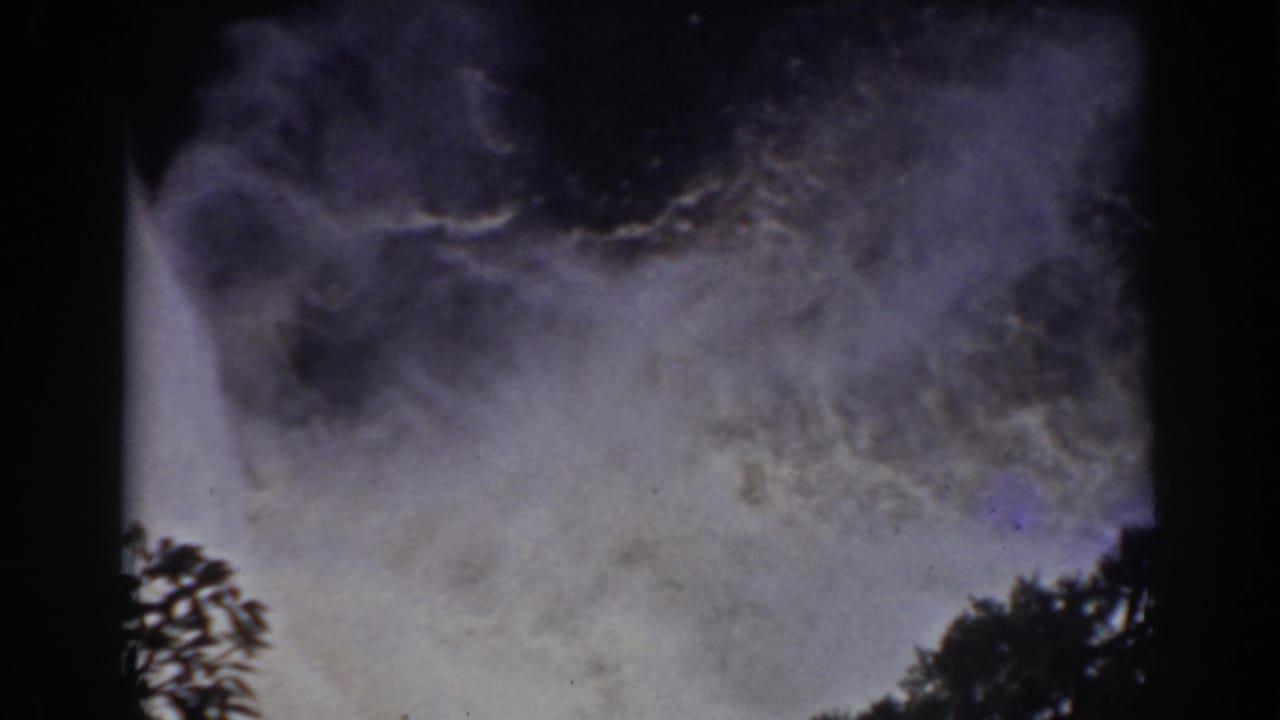 Archival 8mm view of waterfall spray at Mount Washington, with foliage silhouetted against the pale mist.