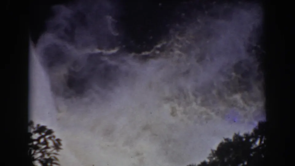 Archival 8mm view of waterfall spray at Mount Washington, with foliage silhouetted against the pale mist.