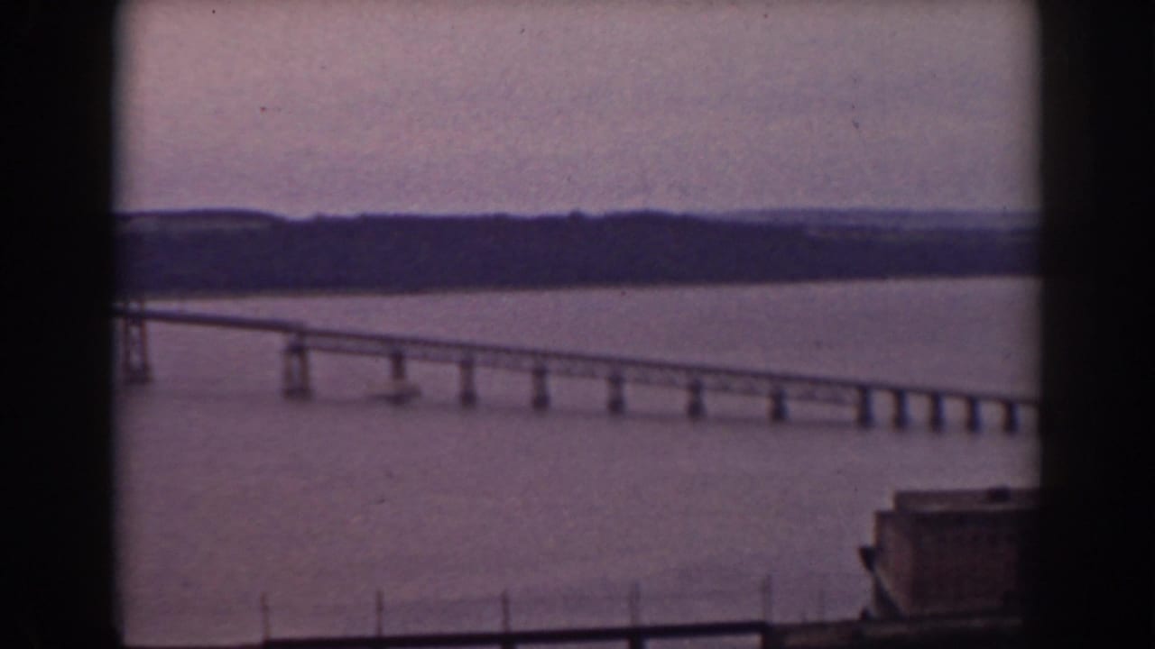 Soft 8mm frame of a long bridge crossing a lake in New Hampshire, partly obscured by the window framing.